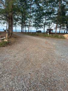 uma estrada de cascalho com árvores ao lado de uma praia em Casaria Beach em Paka