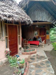 Lushoto的住宿－Irente Kinyonga Cottage，两个人坐在房子的门廊上