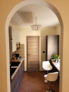um arco leva a uma cozinha com uma cadeira branca em Dimora Duomo em Imola