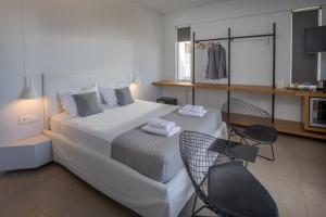 een slaapkamer met een groot wit bed en 2 stoelen bij Basilico Suites Adults Only in Gouves