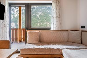 a living room with a couch and a large window at Blosegghof Bergchalets Talblick in Racines