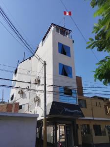 um edifício branco com uma bandeira vermelha em cima em Hospedaje Diamantes em Huacho