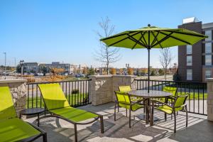 un patio con mesa, sillas y sombrilla en SpringHill Suites by Marriott Menomonee Falls, en Menomonee Falls