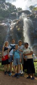 a group of people standing in front of a waterfall at Irente Kinyonga Cottage in Lushoto