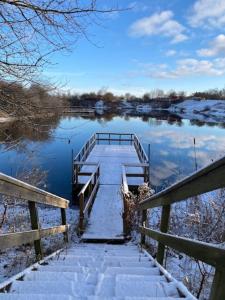 eine Holzbrücke über einen See mit Schnee darauf in der Unterkunft Lantgård nära stad, fiske o golf in Malmö