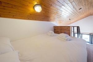 een slaapkamer met een groot wit bed en een houten plafond bij Skyhook: Batiment B in Chamonix-Mont-Blanc