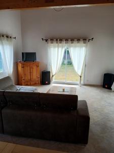 a living room with a couch and a large window at Maison sanguinet à 100m du lac in Sanguinet