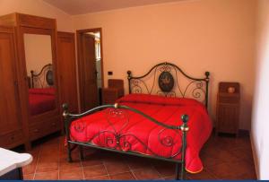 een rood bed met een rood dekbed in een slaapkamer bij VILLA CATERINA in Calasetta