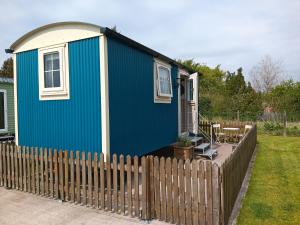 a blue tiny house with a wooden fence at Shepherd Hut Bird Enniskillen, Fermanagh in Enniskillen