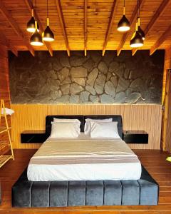 a large bed in a room with a stone wall at Entre Nubes Eco Hotel in El Queremal +16 photos