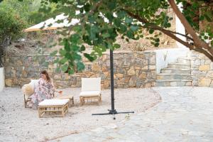 kobieta siedząca na krześle obok dwóch krzeseł w obiekcie The White Rose Hotel w Poros