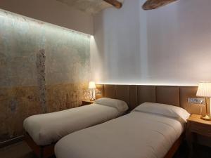 2 camas en una habitación pequeña con 2 lámparas en Casa Clotilde - Apartamento elegante y cómodo en Sant Joan de les Abadesses, en Sant Joan de les Abadesses