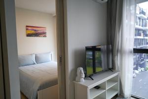 1 dormitorio con 1 cama, TV y ventana en Modern 2-bedroom Apartments. Skypark Laguna (Bang Tao) en Bang Tao Beach