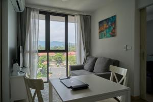 sala de estar con mesa, sofá y ventana en Modern 2-bedroom Apartments. Skypark Laguna (Bang Tao) en Bang Tao Beach