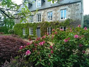 een stenen huis met roze bloemen ervoor bij Le domaine des Ecureuils in Vassy