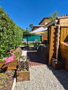 a wooden deck with a pink flamingo in a garden at Chez Florence et Bruno in Saint-Cyr-sur-Mer