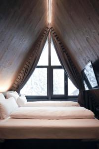 a bed in a room with a large window at TRIFORÊT alpinresort in Hinterstoder
