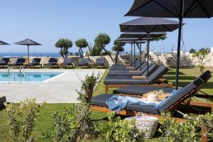 - une rangée de chaises longues et de parasols à côté de la piscine dans l'établissement Basilico Suites Adults Only, à Gouves