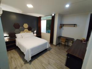 Schlafzimmer mit einem großen weißen Bett und einem Schreibtisch in der Unterkunft Hospedaje Diamantes in Huacho