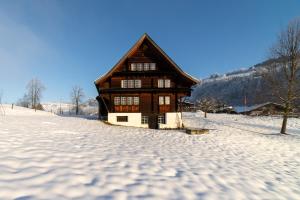 uma casa de madeira na neve em frente em Chammern em Nesslau