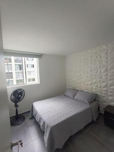 a white bedroom with a bed and a window at Apartamento en el sur de Cali in Cali