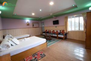 a bedroom with a bed and a couch and a tv at Hotel Mount Paradise in Nagarkot