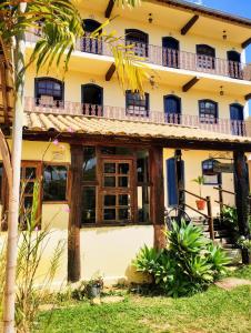 a large yellow building with windows and a balcony at Pousada Luz do Sol in Carrancas