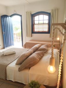 a bedroom with a bed with pillows and a window at Pousada Luz do Sol in Carrancas