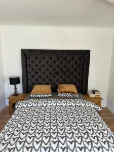 - une chambre avec un grand lit et une tête de lit noire dans l'établissement Hugo apartment, à Šiauliai