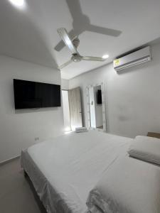 a bedroom with a large white bed and a ceiling fan at lujoso apartamento central con tres Aires acondicionados y parqueo in Montería