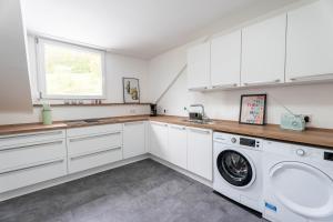 a kitchen with white cabinets and a washer and dryer at großzügiges, stylisches Apartment I 6 Personen I Eifel I Naturliebhaber I in Metterich