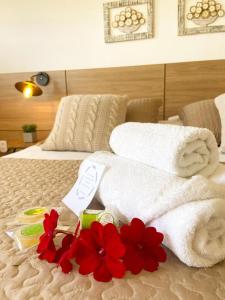 a hotel room with towels and red flowers on a bed at Pousada Luz do Sol in Carrancas