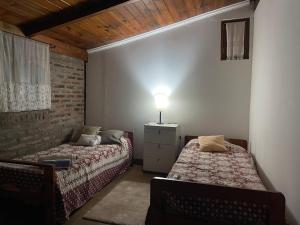 a bedroom with two beds and a lamp on the wall at Anita Haus Casa de fin de semana in Garupá