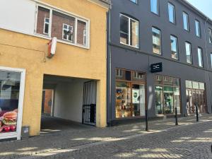 an empty street with a building and a sandwich shop at aday - 1 bedroom balcony apartment on the pedestrian street in Randers in Randers