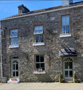 ein altes Steingebäude mit Fenstern und einer Markise in der Unterkunft The Old Exchange in Clifden