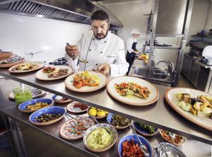 un chef en una cocina que prepara platos de comida en Riva di Ugento Beach Camping Resort, en Ugento