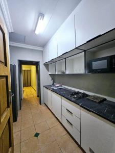 eine Küche mit weißen Schränken und schwarzen Arbeitsplatten in der Unterkunft ZUCH Accommodation At Pafuri Self Catering - Comfort Apartment in Polokwane