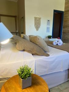a bed with pillows on top of it with a table at Pousada Luz do Sol in Carrancas