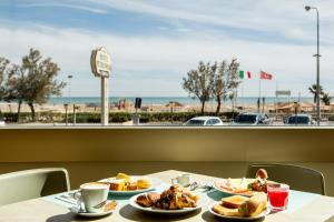 a table with plates of food and a view of the beach at Hotel Metropole in Rimini