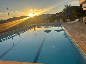 a swimming pool with the sunset in the background at Recanto da Felicidade in São Lourenço