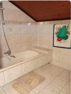 a bathroom with a tub and a tile wall at S.T Family Apartement in Kalabaka