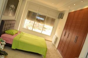 Schlafzimmer mit einem Bett, einem Fenster und einer Tür in der Unterkunft Superbe appartement a La Marsa in La Marsa
