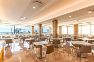 リミニにあるHotel Metropoleのテーブルと椅子が備わり、海の景色を望むレストラン