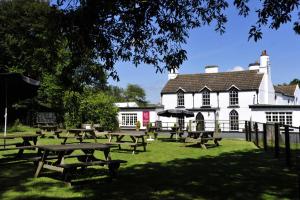 un grupo de mesas de picnic frente a un edificio en Tudor Lodge Bed & Breakfast, en Manorbier