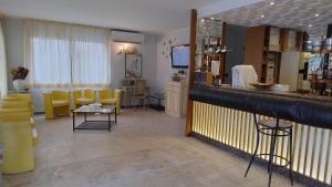 un salón con un bar con sillas amarillas y espejo en Hotel Rosy, en Bellaria-Igea Marina