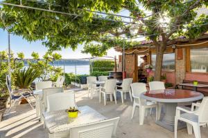 un patio con mesas y sillas y vistas al océano en Apartments Jurica - Sea View & Boat Mooring en Barbat na Rabu
