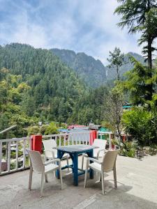 uma mesa e cadeiras numa varanda com vista para uma montanha em Hostel 360 Degree Jibhi em Jibhi