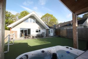 a backyard with a hot tub on a lawn at Four Corners Holiday Home Hot Tub & Sauna in Ferndown