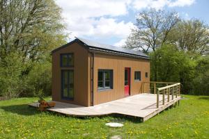 a tiny house with a deck in a field at Les Jours Heureux Tiny House in Villers-le-Gambon