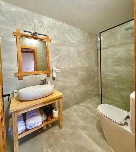 a bathroom with a sink and a mirror and a toilet at Guesthouse Vitoria - Mrizi i Zanave in Fishtë